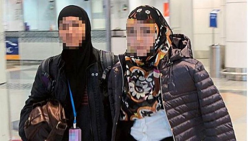 Офицер полиции (слева), сопровождает женщину, пытавшуюся уехать в Сирию к "мужу", боевику "Исламского государства. Фото Straits Times.